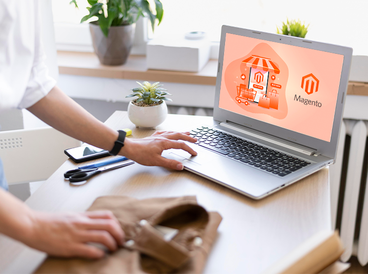 Persona usando una laptop que muestra la pantalla de Magento con ilustración de tienda online y logo de Magento en color naranja.